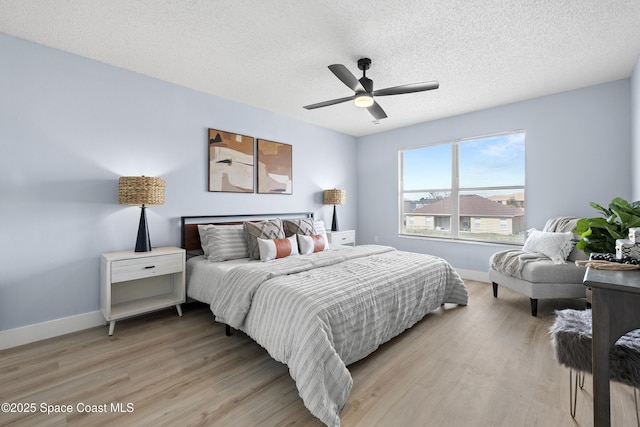 bedroom featuring ceiling fan, light hardwood / wood-style floors, and a textured ceiling