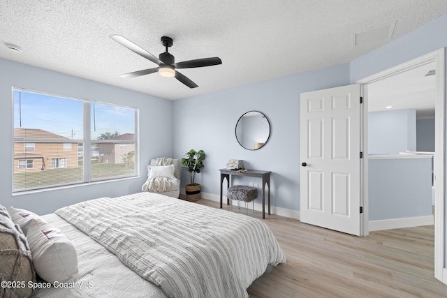 bedroom featuring ceiling fan, a textured ceiling, and light hardwood / wood-style floors