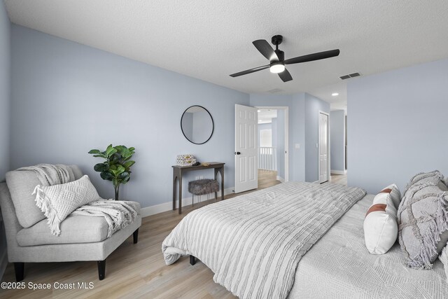 bedroom featuring ceiling fan, a textured ceiling, and light wood-type flooring