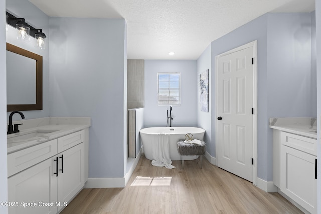 bathroom with hardwood / wood-style floors, vanity, a washtub, and a textured ceiling