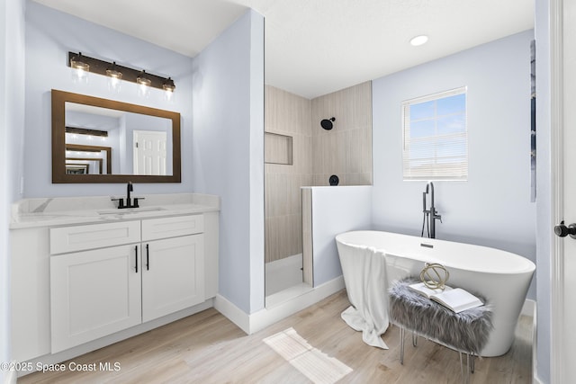 bathroom featuring wood-type flooring, shower with separate bathtub, and vanity