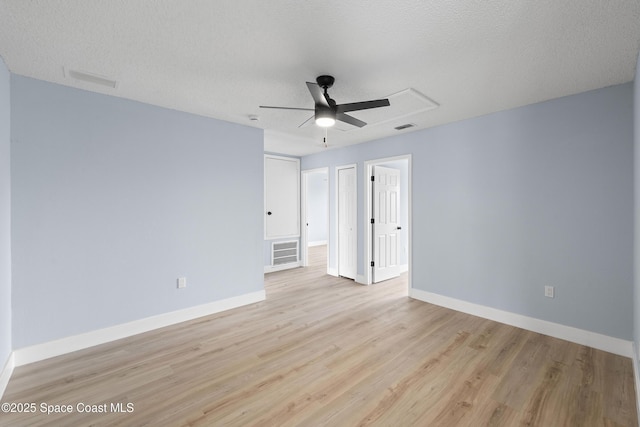 empty room with ceiling fan, light hardwood / wood-style flooring, and a textured ceiling