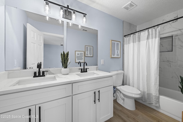 full bathroom with shower / bath combination with curtain, hardwood / wood-style flooring, vanity, toilet, and a textured ceiling