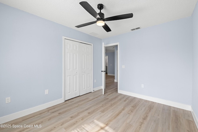 unfurnished bedroom with ceiling fan, light hardwood / wood-style floors, a closet, and a textured ceiling