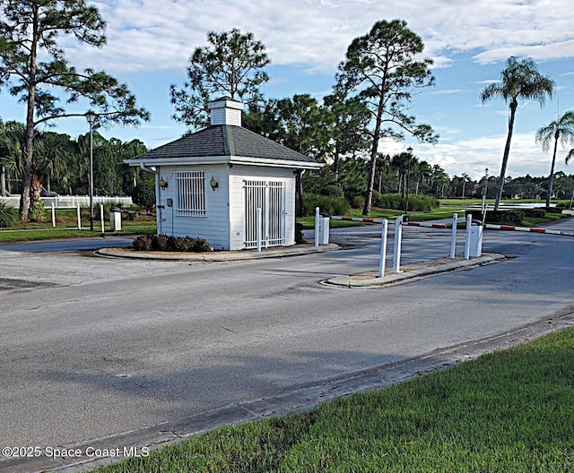 view of road featuring curbs, street lighting, and a gated entry