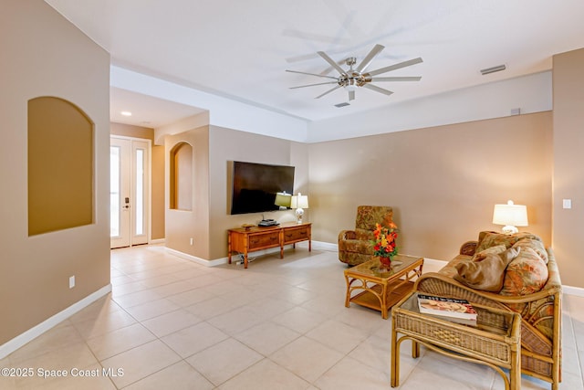 living room featuring visible vents, a ceiling fan, arched walkways, light tile patterned floors, and baseboards