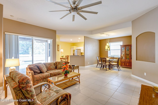 living area featuring light tile patterned floors, baseboards, and ceiling fan