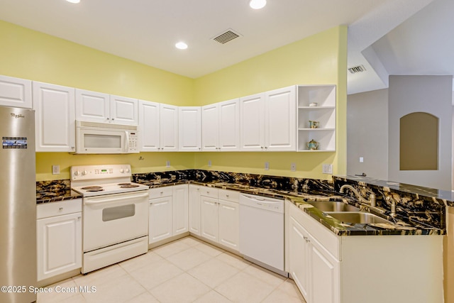 kitchen with dark countertops, a sink, a peninsula, white appliances, and open shelves