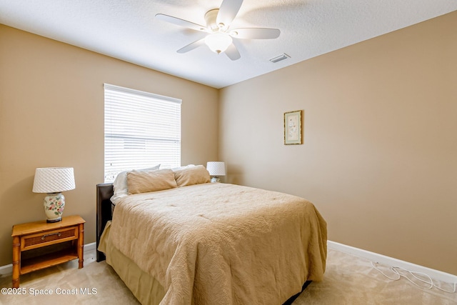 bedroom with a ceiling fan, baseboards, visible vents, a textured ceiling, and light carpet