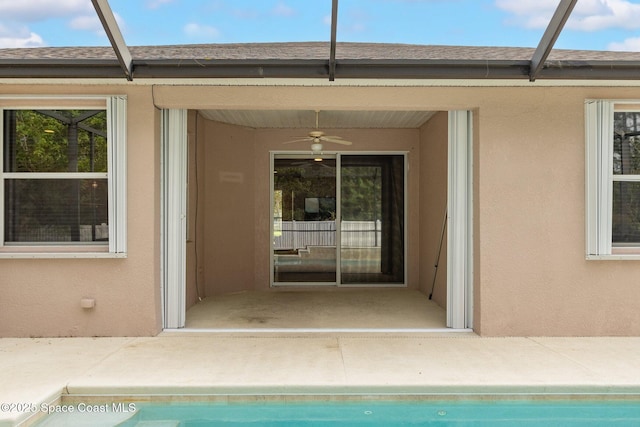 exterior space with a shingled roof, stucco siding, an outdoor pool, a ceiling fan, and a patio