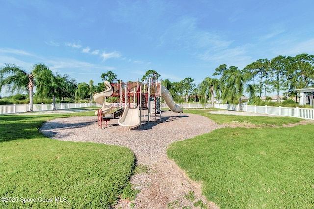 communal playground featuring a yard and fence