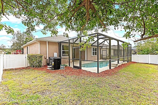 back of property with central air condition unit, stucco siding, a lawn, a fenced backyard, and an outdoor pool