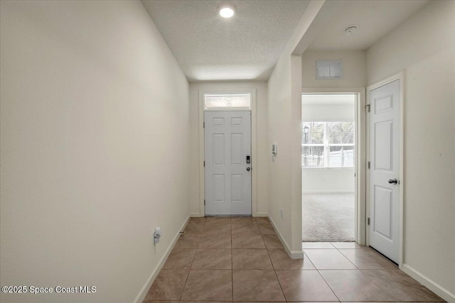 entryway featuring light tile patterned floors and a textured ceiling