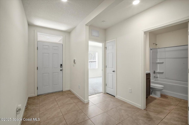 entrance foyer with light tile patterned floors and a textured ceiling