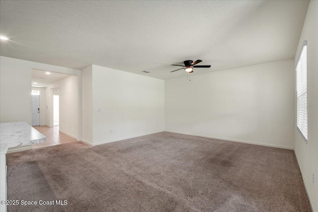 carpeted empty room featuring ceiling fan and a textured ceiling