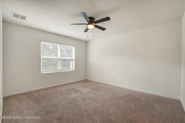 carpeted empty room featuring ceiling fan and a textured ceiling