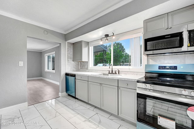 kitchen featuring sink, gray cabinets, appliances with stainless steel finishes, a wealth of natural light, and ornamental molding