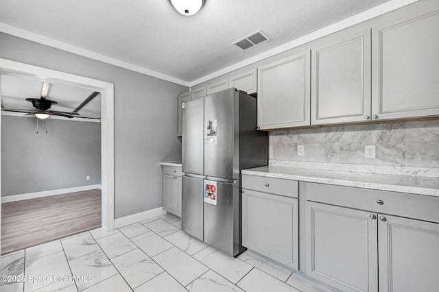 kitchen featuring stainless steel refrigerator, ceiling fan, tasteful backsplash, and gray cabinetry