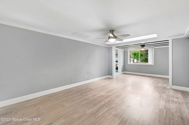 spare room featuring ceiling fan, ornamental molding, a skylight, and light hardwood / wood-style flooring