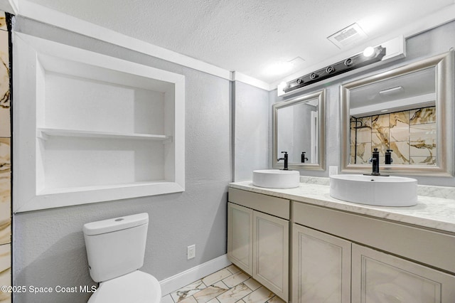 bathroom with vanity, toilet, and a textured ceiling