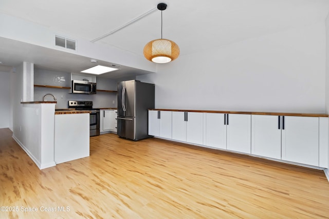 kitchen featuring sink, hanging light fixtures, light wood-type flooring, stainless steel appliances, and white cabinets