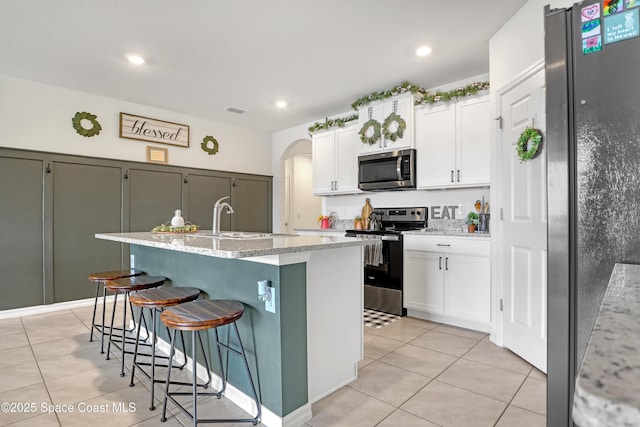 kitchen featuring stainless steel appliances, an island with sink, white cabinets, and light tile patterned flooring