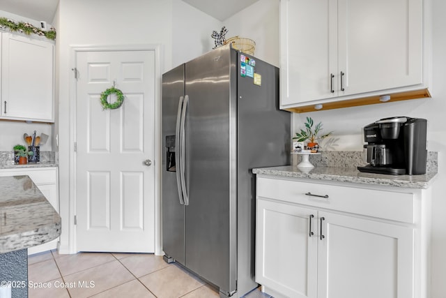 kitchen featuring white cabinetry, stainless steel fridge, light stone countertops, and light tile patterned floors