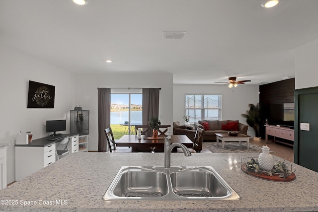 kitchen featuring white cabinetry, plenty of natural light, light stone countertops, and sink