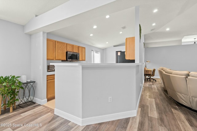 kitchen featuring fridge, lofted ceiling, and light wood-type flooring