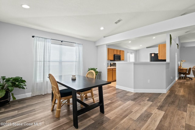 dining room featuring lofted ceiling and wood-type flooring