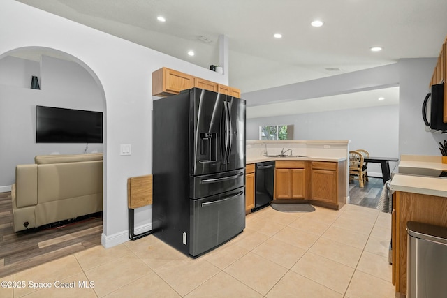 kitchen featuring sink, kitchen peninsula, light tile patterned floors, and black appliances