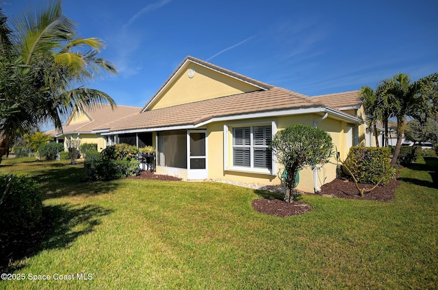 rear view of property with a sunroom and a lawn