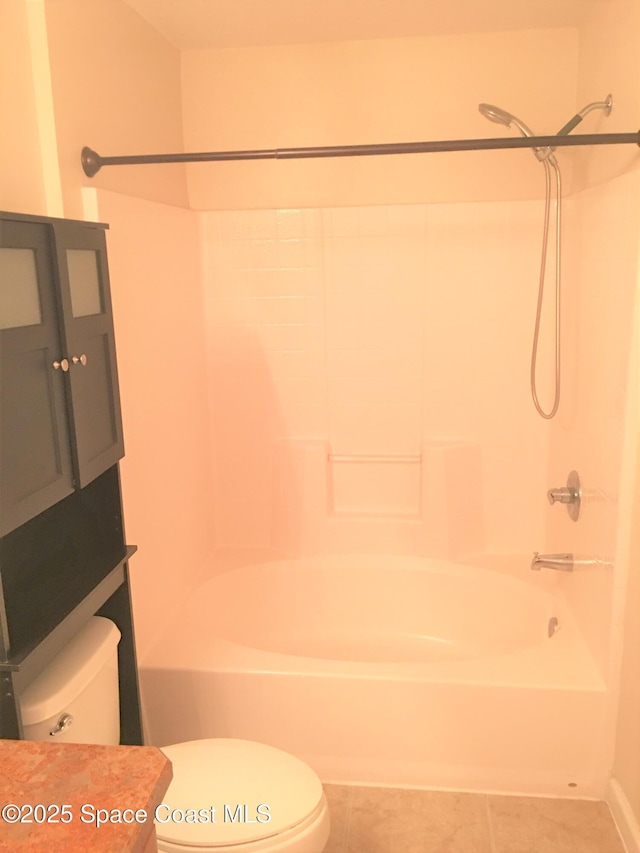 bathroom with tile patterned floors, washtub / shower combination, and toilet