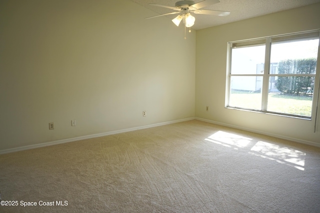 empty room featuring baseboards, a textured ceiling, light carpet, and a ceiling fan