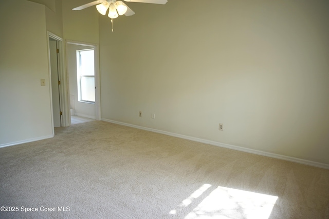 carpeted spare room featuring a ceiling fan and baseboards