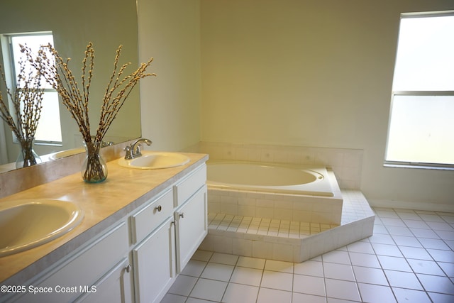 full bath with a sink, a garden tub, double vanity, and tile patterned floors