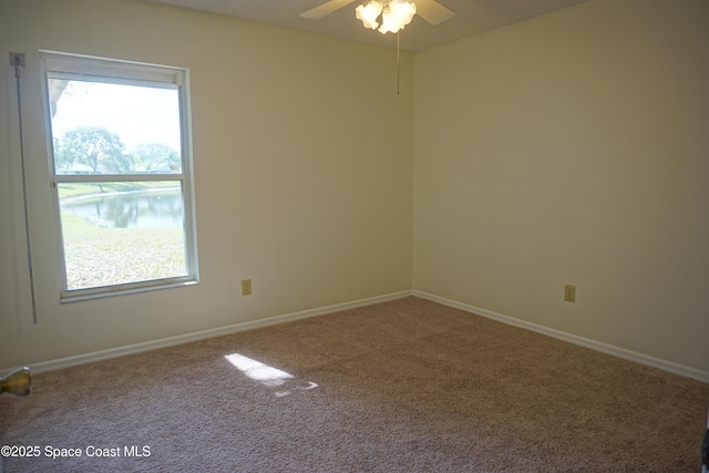 carpeted spare room with ceiling fan and baseboards