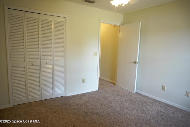 unfurnished bedroom featuring a closet, carpet floors, a textured ceiling, and baseboards