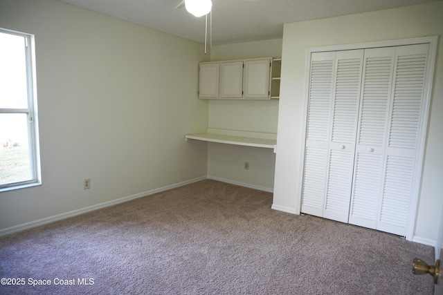 unfurnished bedroom featuring a closet, baseboards, carpet flooring, and built in study area