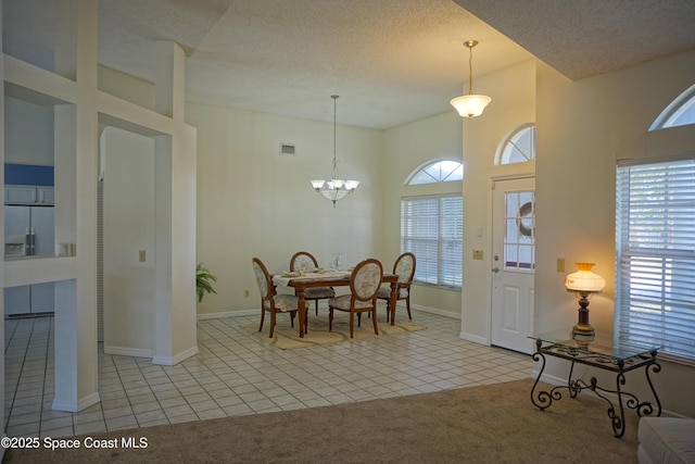 tiled dining area featuring visible vents, a textured ceiling, carpet, a high ceiling, and a chandelier