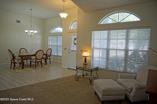 living area with visible vents, baseboards, carpet floors, tile patterned floors, and a textured ceiling