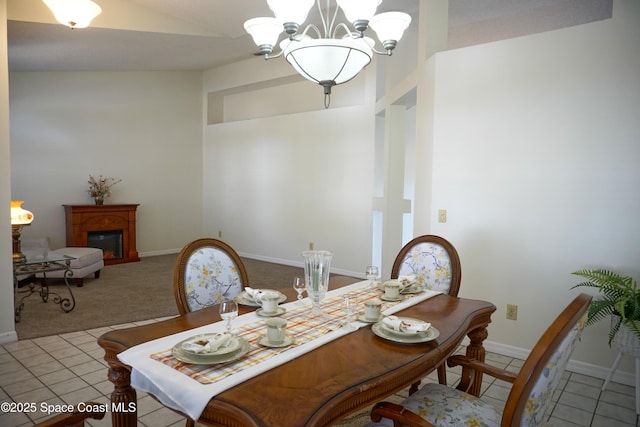 carpeted dining room with a glass covered fireplace, tile patterned floors, baseboards, and an inviting chandelier