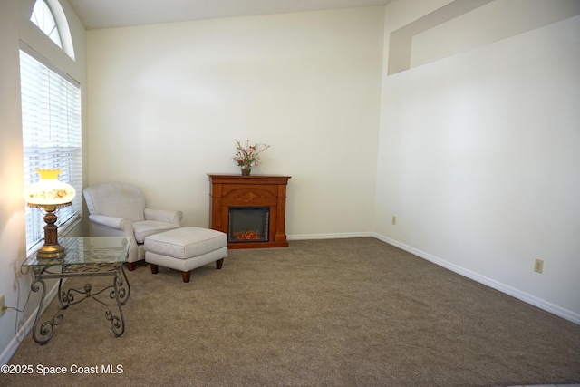 sitting room featuring a glass covered fireplace, carpet, and baseboards