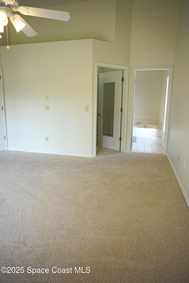 carpeted empty room with a high ceiling and ceiling fan