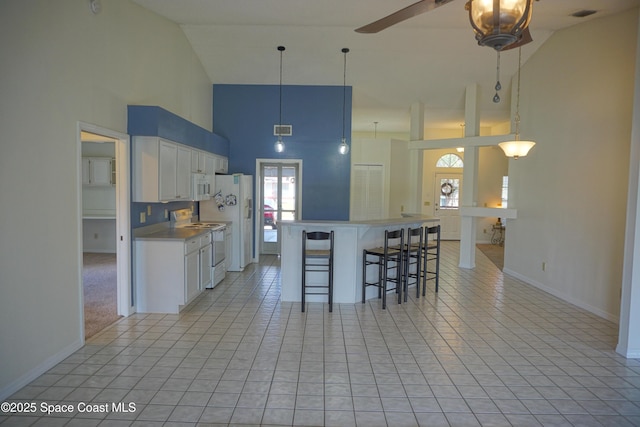 kitchen with visible vents, a kitchen bar, white cabinetry, white appliances, and light tile patterned floors