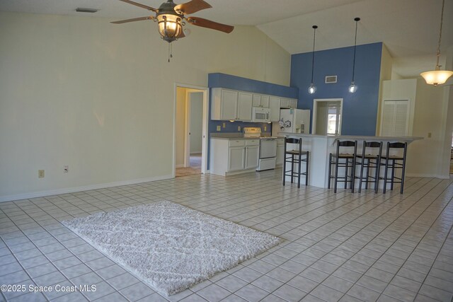 kitchen with white appliances, a kitchen breakfast bar, visible vents, and white cabinets