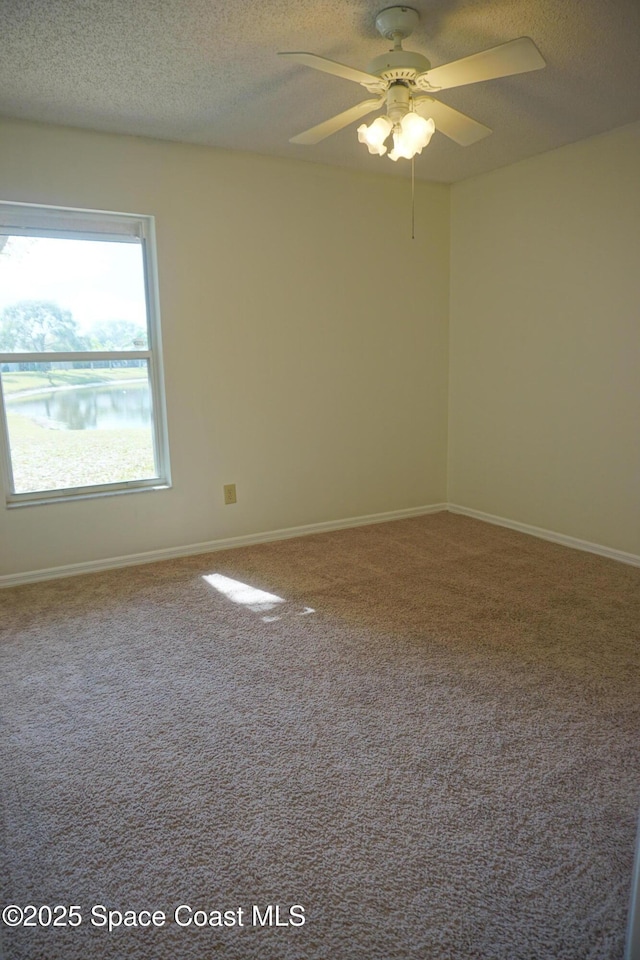 spare room with ceiling fan, carpet, baseboards, and a textured ceiling