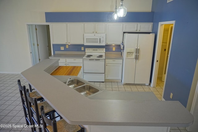 kitchen with a sink, white appliances, light tile patterned flooring, and white cabinetry