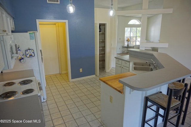 kitchen featuring a kitchen bar, visible vents, an island with sink, a sink, and light tile patterned floors