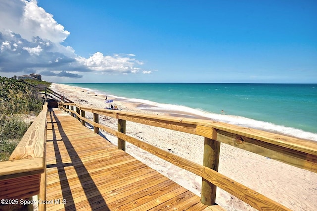 view of dock featuring a water view and a beach view